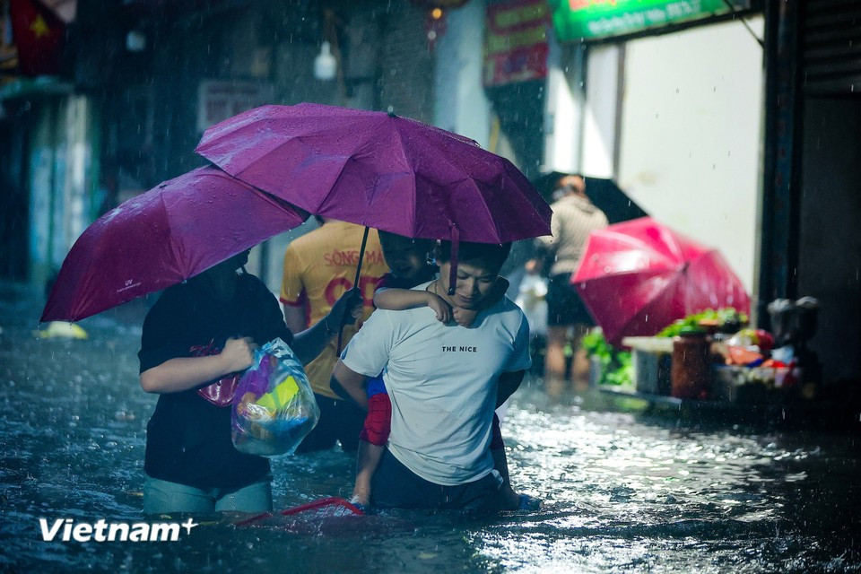 Residents wade through flooded streets to pick up children and shop for groceries at the end of the day. (Photo: Hoai Nam/Vietnam+)