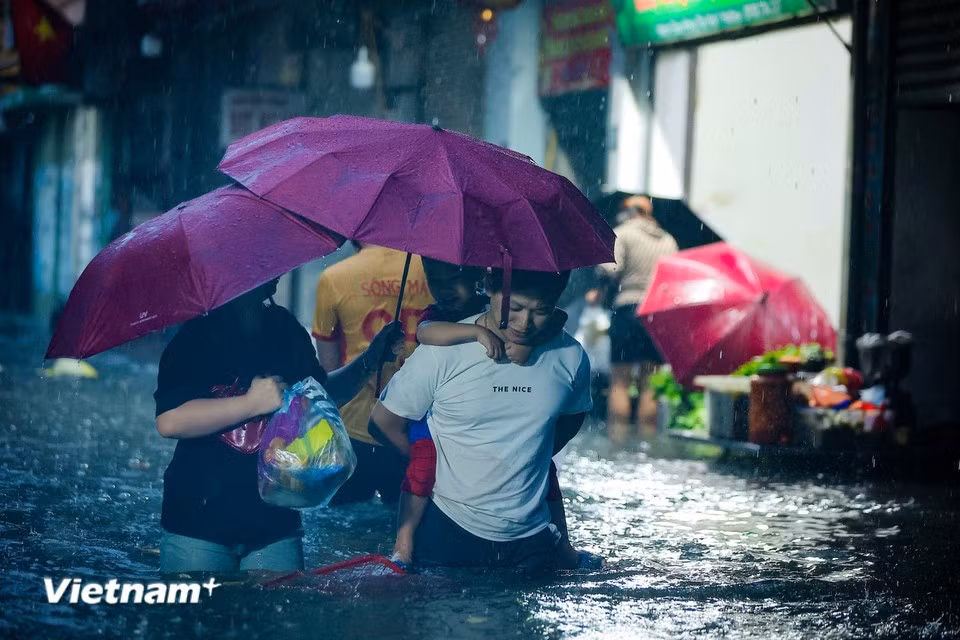Residents wade through flooded streets to pick up children and shop for groceries at the end of the day. (Photo: Hoai Nam/Vietnam+)