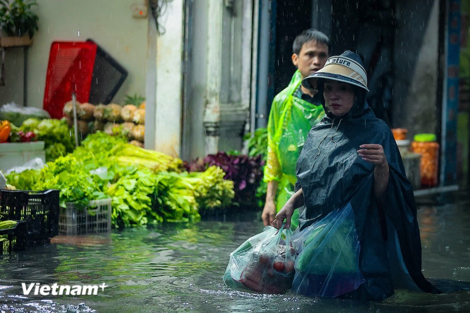To prepare dinner for their families, many wade through waist-deep water to buy food in areas not yet heavily flooded. (Photo: Hoai Nam/Vietnam+)