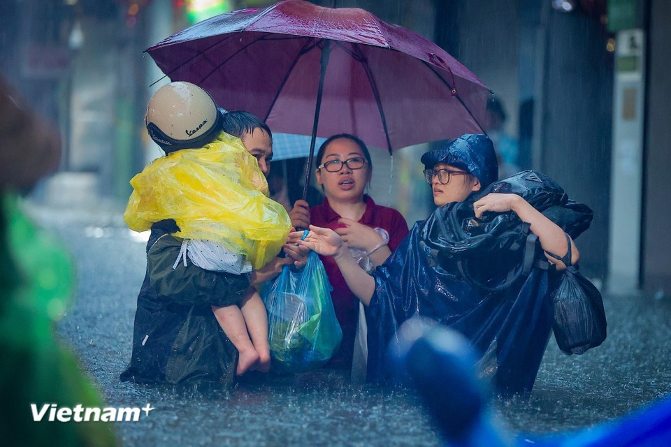 Parents struggle to pick up their children from school through the floodwaters. (Photo: Hoai Nam/Vietnam+)