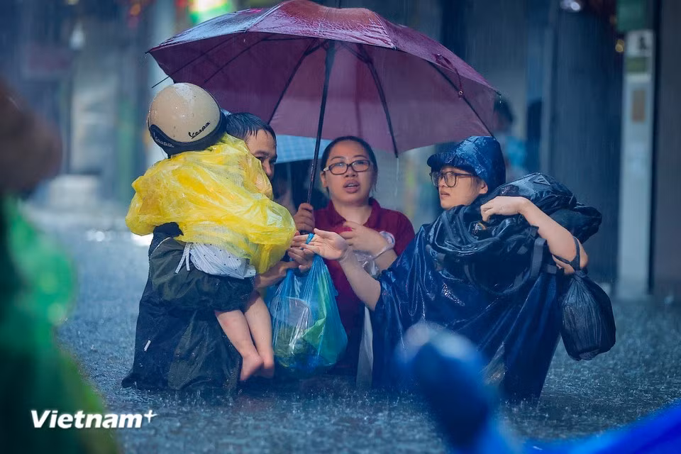 Parents struggle to pick up their children from school through the floodwaters. (Photo: Hoai Nam/Vietnam+)