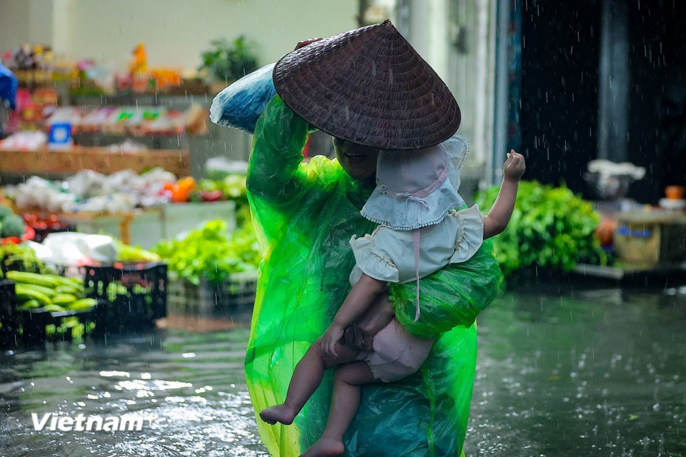 Parents struggle to pick up their children from school through the floodwaters. (Photo: Hoai Nam/Vietnam+)