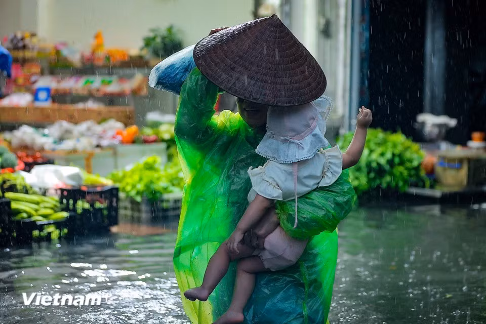 Parents struggle to pick up their children from school through the floodwaters. (Photo: Hoai Nam/Vietnam+)