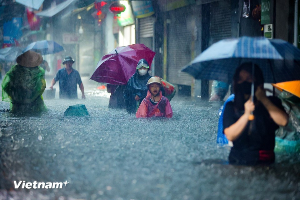 A stream of people moves through roads now turned into rivers. (Photo: Hoai Nam/Vietnam+)