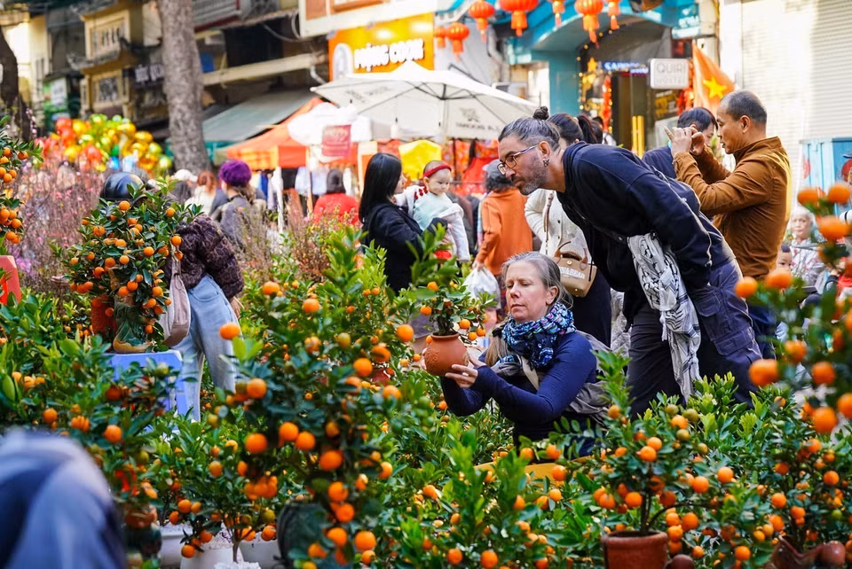 Foreign tourists join in the festive spirit of Tet shopping alongside Vietnamese locals. (Photo: Khanh Hoa – VNA)