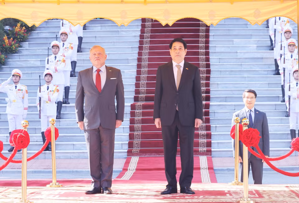 State President Luong Cuong and King Abdullah II ibn Al Hussein of the Hashemite Kingdom of Jordan stand on the reviewing stand as the military band plays the national anthems of both countries. (Photo: Lam Khanh – VNA)