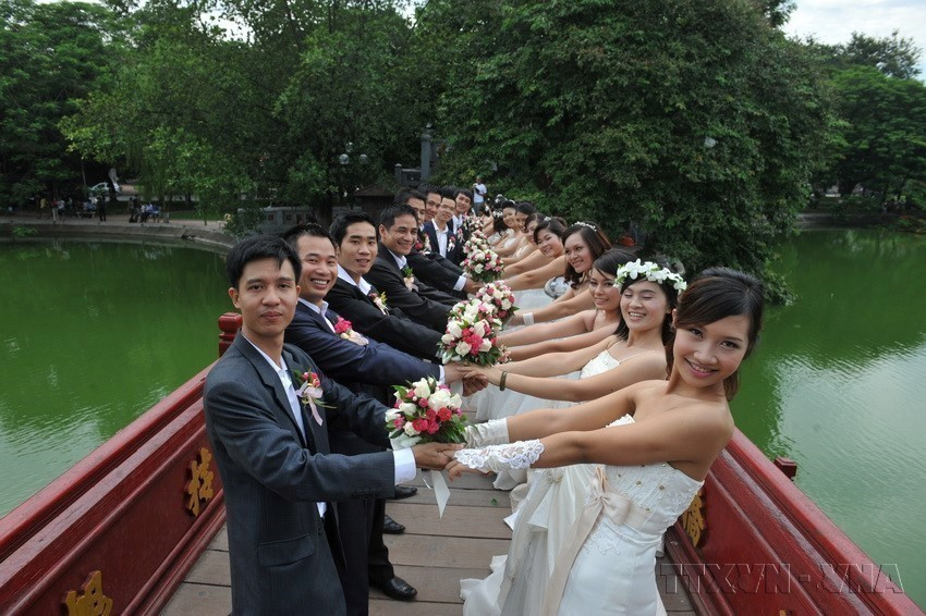 Fifty couples from across the country pose for a group wedding photo at Hoan Kiem Lake in Hanoi. (Photo: VNA)