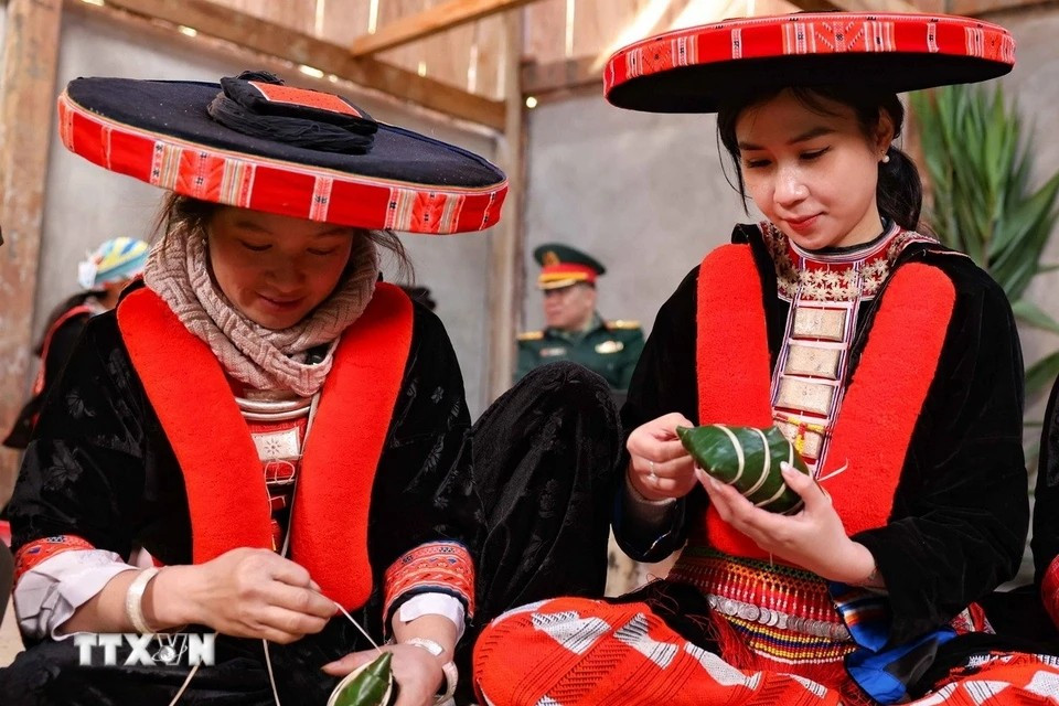 A female tourist from Hanoi, dressed in traditional Red Dao attire from Nguyen Binh, eagerly joins in making "banh chung gu" for Tet. (Photo: Thanh Tung/VNA)