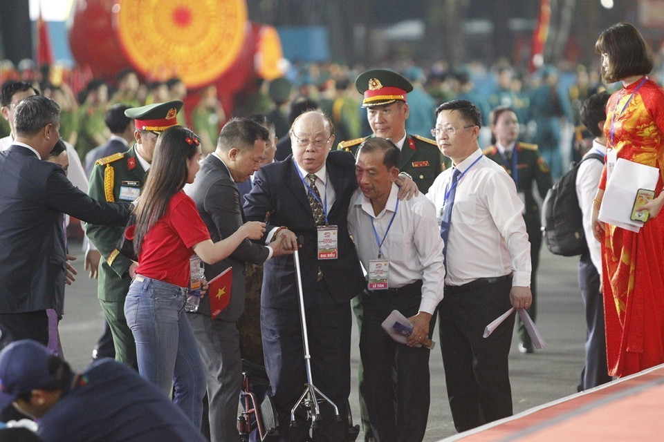 An elderly delegate receives assistance to reach his seat in the grandstand. (Photo: VNA)