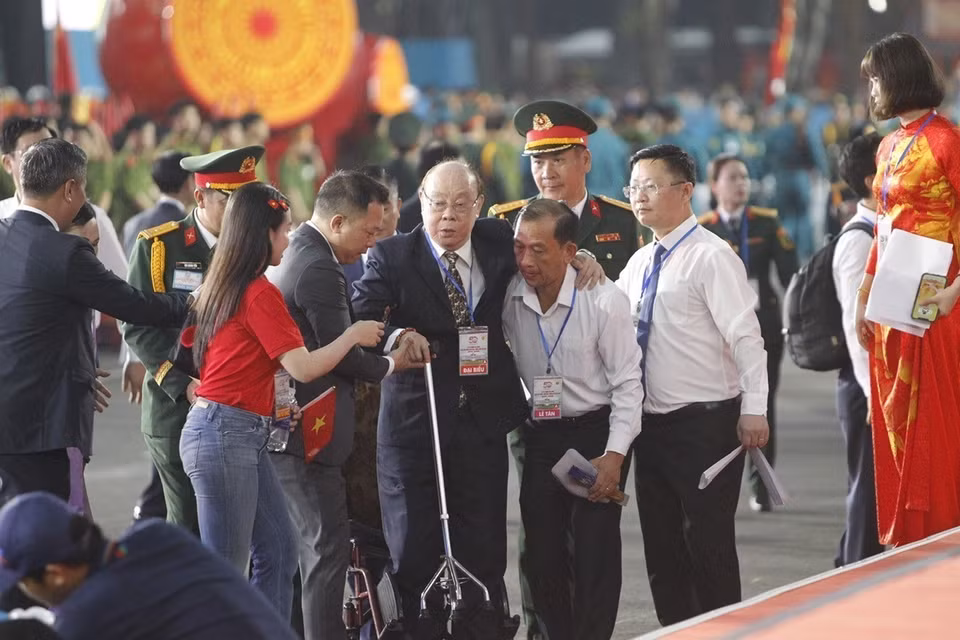 An elderly delegate receives assistance to reach his seat in the grandstand. (Photo: VNA)