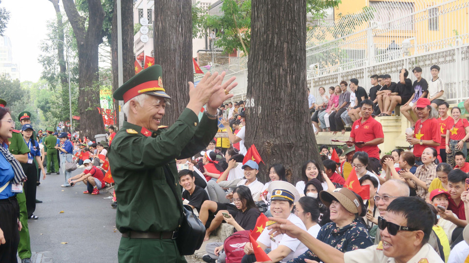 A veteran leads the crowd in singing "As if Uncle Ho Were Here on the Great Victory Day" while waiting for the parade. Photo: VNA