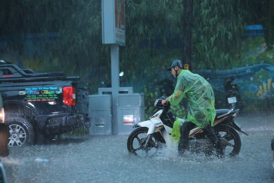 Many motorcyclists walk their vehicles through the flood due to heavy rain. (Photo: Hoang Hieu – VNA)