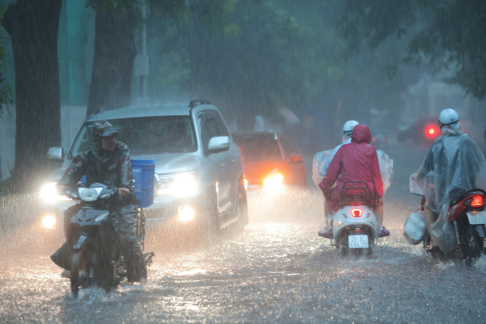 Torrential rain leaves Hang Bai Street heavily flooded, forcing cars to turn on their headlights while moving. (Photo: Hoang Hieu – VNA)