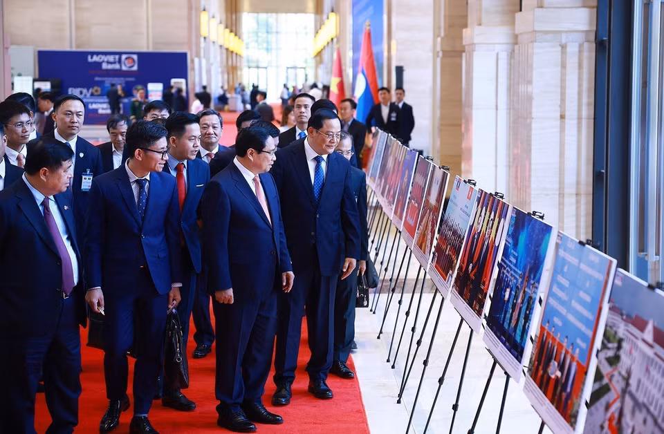 Prime Minister Pham Minh Chinh and Lao Prime Minister Sonexay Siphandone visit a photo exhibition on cooperation between the two countries. (Photo: Duong Giang - VNA)
