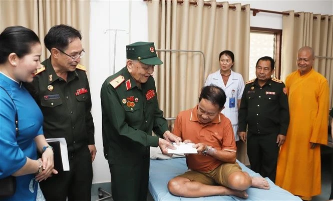 Major General Vo Van Chot, head of Nghe An province’s liaison board for former Vietnamese volunteer soldiers and military experts in Laos, presents a gift to a patient at Military Central Hospital 103 of Laos. (Photo: VNA)