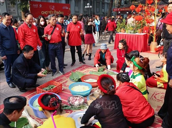 Making banh chung (Vietnam’s traditional square glutinous rice cake) at the Hanoi Red Cross Society's charity market on January 4. (Photo: VNA)