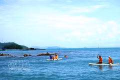 Tourists experience stand-up paddleboarding (SUP) along the coastal waters of the Hai Tac island. (Photo: VNA)