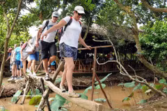 Foreign tourists enjoy crossing a handmade bridge in the Mekong Delta. (Photo: VNA) 