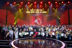 Party General Secretary To Lam and Minister of National Defence General Phan Van Giang pose for a photo with the award-winning authors and author groups. (Photo: VNA)