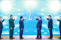 Prime Minister Pham Minh Chinh (third from right) and officials launch the Ministry of Construction’s new information technology systems at the conference on December 21. (Photo: VNA)