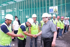 Prime Minister Pham Minh Chinh (R) encourages workers and engineers at the Vietnam Exhibition Fair Centre project site. (Photo: VNA)