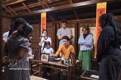 Tourists watch a calligraphy master demonstrate the art in a heritage setting during the Temple of Literature's night tour. (Photo: VNA)