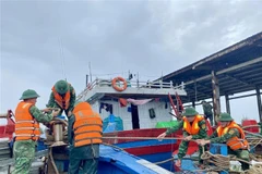 Border guards assist fishermen in reinforcing and securing their boats. (Photo: VNA)