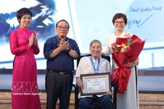 From left, Vietnam News Agency General Director Vu Viet Trang and Jury Chairman, poet Tran Dang Khoa congratulate "Cricket Knight" songwriter Pham Tuyen and his daughter, Pham Hong Tuyen, at the De Men Awards ceremony in Hanoi on May 28, 2025. (Photo: VNA)
