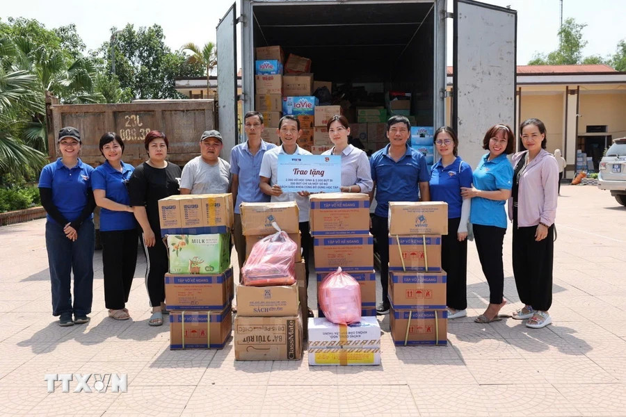 Representatives from the Vietnam News Agency Communication Development Centre presents 2,000 notebooks, 2,000 ballpoint pens, 500 pencils, along with textbooks and other school supplies, to a school affected in Ha Hoa district. (Photo: Ta Toan/VNA