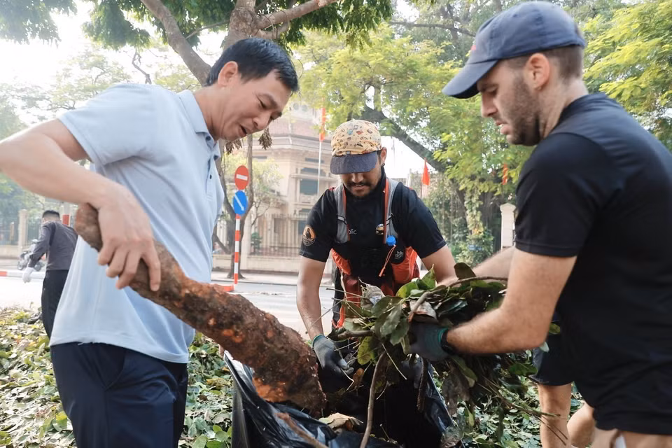 Foreigners join in clearing fallen tree branches on the streets in Hoan Kiem district. (Photo: VNA)