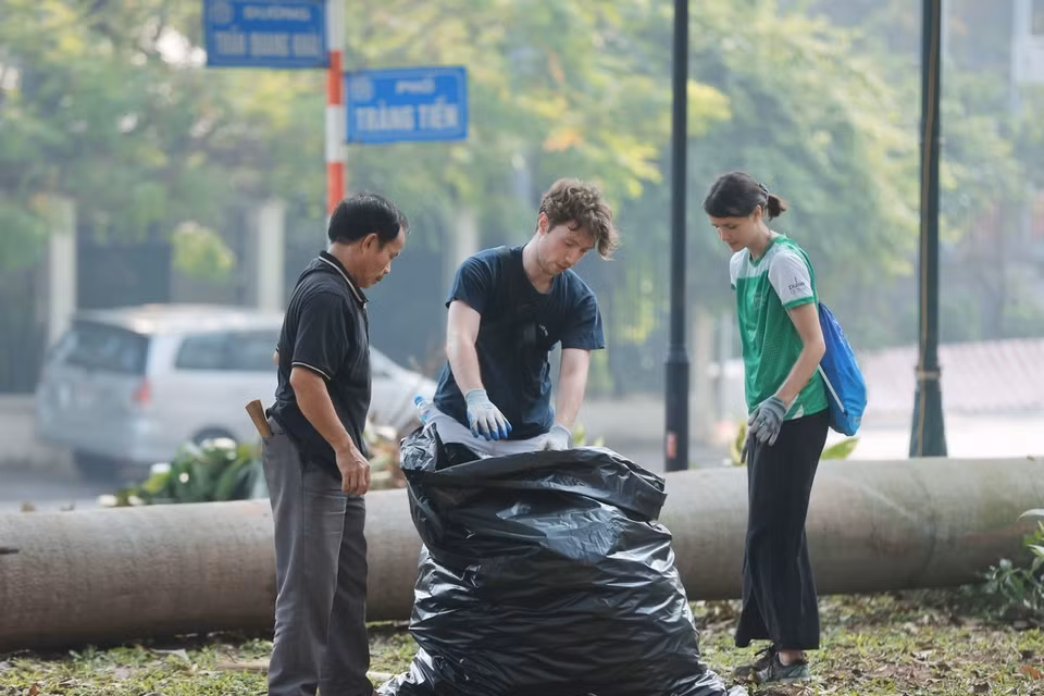 Foreign volunteers collect trash in the Bac Co garden area, Hoan Kiem district. (Photo: VNA)