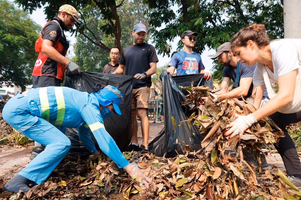 Foreigners join local residents in cleaning up trash along Hanoi's streets after Typhoon Yagi. (Photo: VNA)