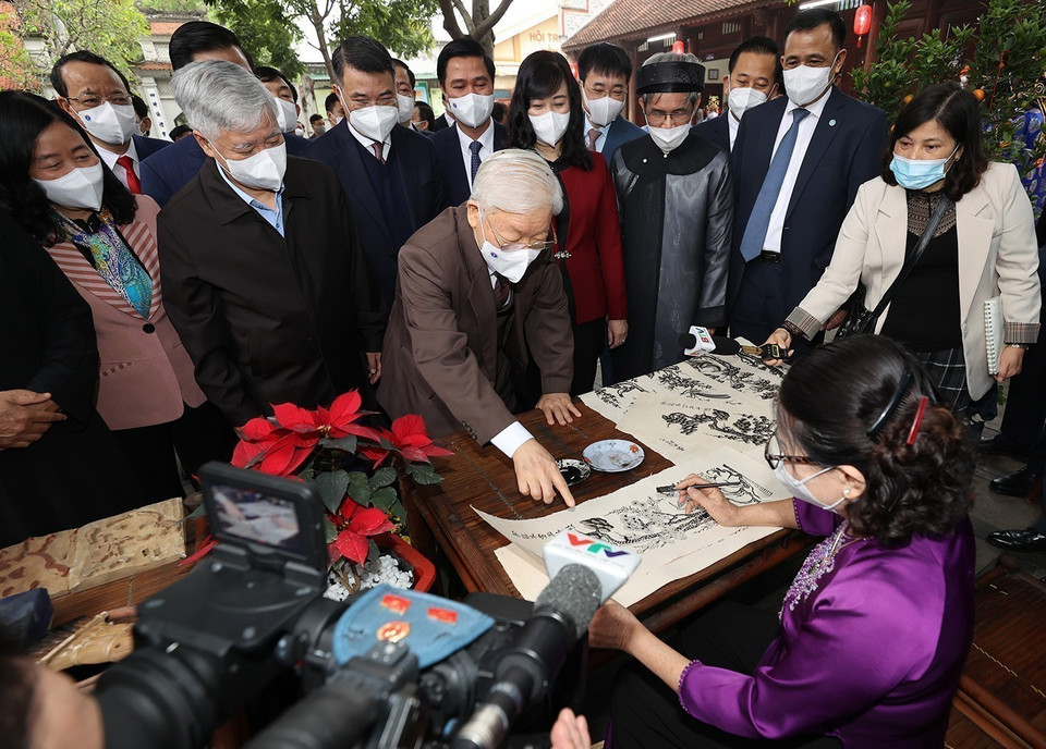 Party General Secretary Nguyen Phu Trong takes a closer look at the making of Dong Ho folk paintings at Den Do historical-cultural relic site in Dinh Bang ward, Tu Son city while visiting local authorities and people of Bac Ninh province on the occasion of traditional Lunar New Year (Tet holiday) (January 24, 2022). (Photo: Tri Dung – VNA)