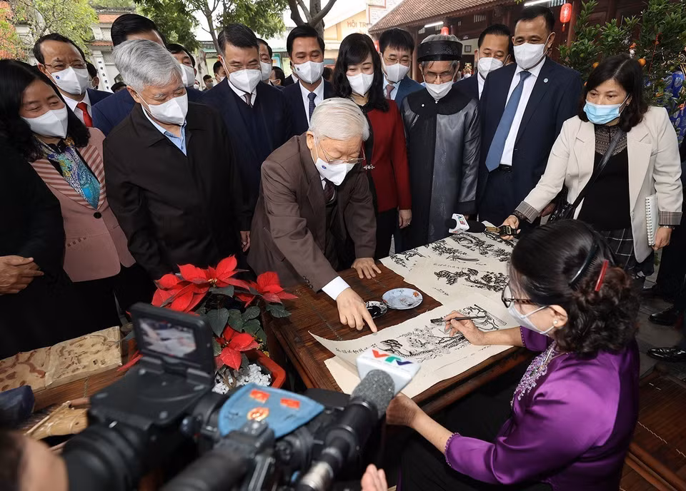Party General Secretary Nguyen Phu Trong takes a closer look at the making of Dong Ho folk paintings at Den Do historical-cultural relic site in Dinh Bang ward, Tu Son city while visiting local authorities and people of Bac Ninh province on the occasion of traditional Lunar New Year (Tet holiday) (January 24, 2022). (Photo: Tri Dung – VNA)