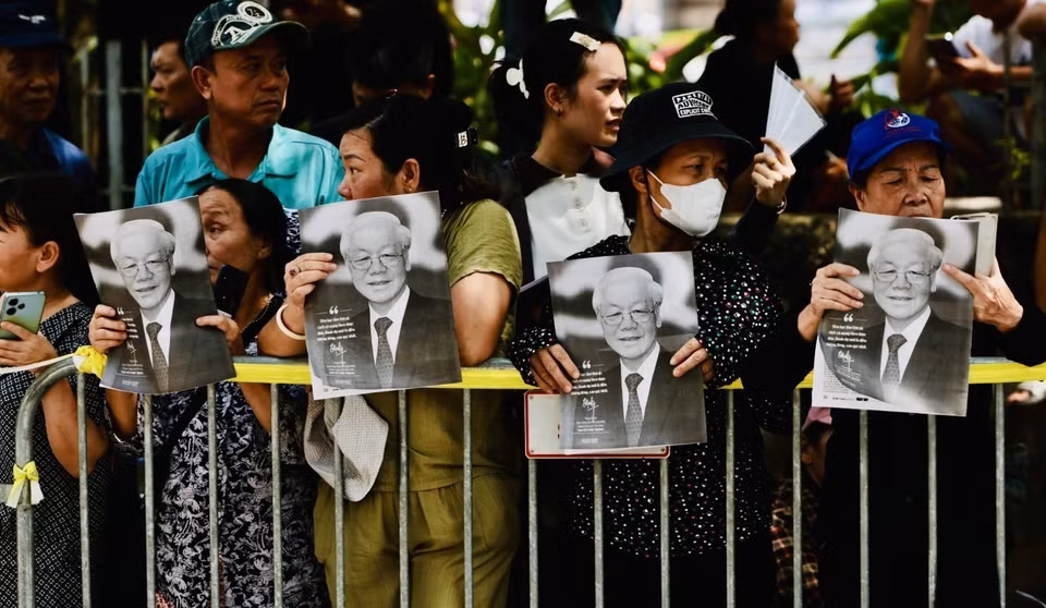 Citizens hold portraits of Party General Secretary Nguyen Phu Trong to bid farewell to him. (Photo: Tran Viet – VNA)