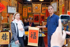 International visitors experience the traditional new year calligraphy activity (Photo: VNA)