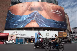 Motorists ride past an anti-US billboard referring to President Donald Trump and the Strait of Hormuz at Valiasr Square in Tehran on May 2, 2026. ( Photo: AFP) 