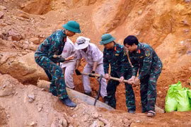 A MAG explosive ordnance disposal team, in coordination with Bo Trach commune's Military Command, safely handles an unexploded bomb for transport to a disposal site. (Photo: VNA) 