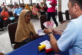 A social worker hands cash assistance to an elderly beneficiary of the Family Hope Programme (PKH) in Madiun City, East Java, on March 14, 2025. (Photo: ANTARA)