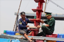 A fishing vessel owner and officers of the Dak Lak provincial Border Guard Command inspect the vessel monitoring system (VMS) on board. (Photo: VNA)