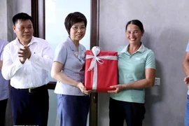 General Director of the Vietnam News Agency (VNA) Vu Viet Trang (C) presents gift for a disadvantaged family in Tuyen Quang, whose new house is built with financial support from the VNA. (Photo: VNA)