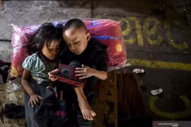 Two children play with a gadget in Jakarta. (Photo: ANTARA)