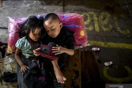 Two children play with a gadget in Jakarta. (Photo: ANTARA)