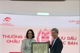 Director of the State Records and Archives Department of Vietnam Dang Thanh Tung presents Elena Bezdetko, spouse of the Russian Ambassador to Vietnam, with a woodblock print of Vietnam’s national title (Photo: VNA) 
