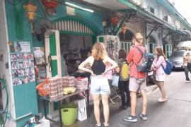 Two foreign tourists buy curry puffs at the popular Khun Phu shop in the Talat Noi community in Bangkok on Monday. (Photo: bangkokpost.com) 