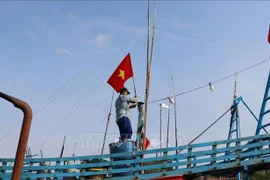 Fishermen raise the national flag before heading out to the sea to affirm Vietnam’s sovereignty over its seas and islands. (Photo: VNA)