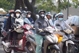 Motorbike riders in Huế City wear sun-protective gear as they travel along Trần Hưng Đạo Street amid the intense heatwave. (Photo: VNA) 