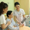 A medical worker at the University Medical Centre Ho Chi Minh City use tablets to update and share information with a patient. (Photo: VNA)