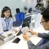 A customer conducts a transaction at an office of a bank in Hanoi (Photo: VNA)