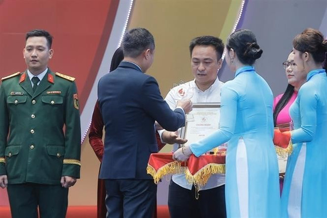 A photojournalist from the Vietnam News Agency receives the third prize at the award ceremony. (Photo: VNA) vna-potal-le-trao-giai-bao-chi-toan-quoc-vi-su-nghiep-phat-trien-van-hoa-viet-nam-lan-thu-ba-8391545-1.jpg